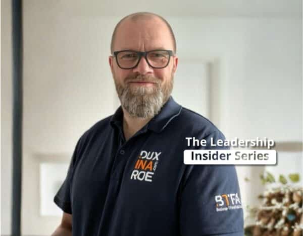 Man with glasses and a beard wearing a dark polo shirt with logos stands indoors; text overlay reads “The Leadership Insider Series,” exploring insights from neuroscience.