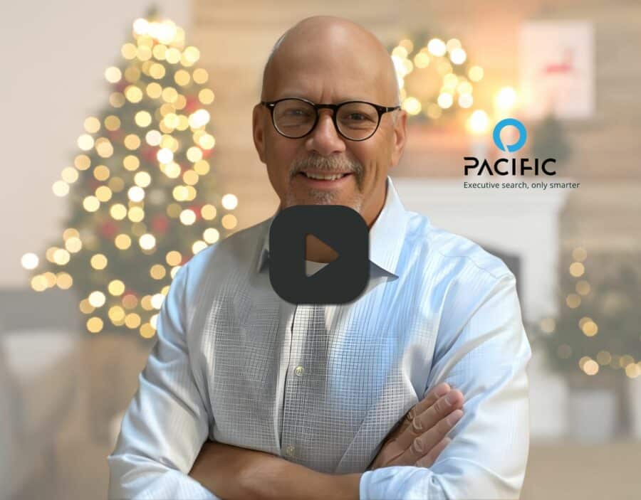 Bald man with glasses smiling, wearing a light shirt, stands in front of a blurred Christmas tree; Pacific logo and slogan appear on the right.