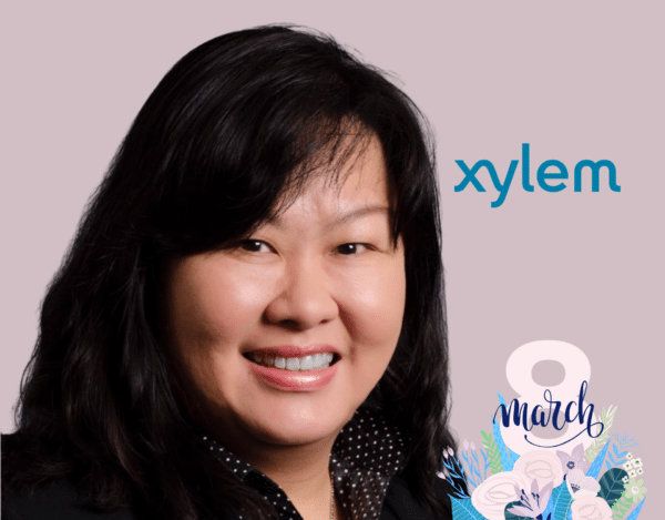 A woman smiling in front of a light background with the Xylem logo and "8 March" International Women’s Day graphic in the corner.