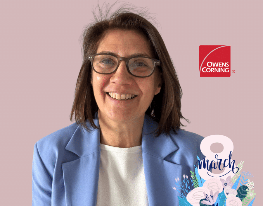Smiling woman with glasses in a light blue blazer, Owens Corning logo on the right, and a “8 March” floral graphic in the bottom corner.