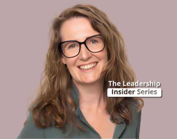Smiling woman with wavy light brown hair and glasses, wearing a green blouse, in front of a plain background with text reading "The Leadership Insider Series.