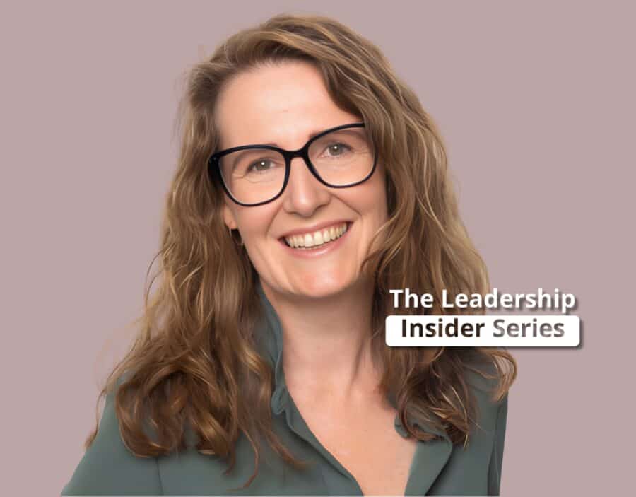 Smiling woman with wavy light brown hair and glasses, wearing a green blouse, in front of a plain background with text reading "The Leadership Insider Series.